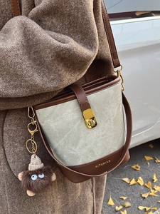 Fashionable grey canvas bucket bag with brown leather trim and cute plush monster charm