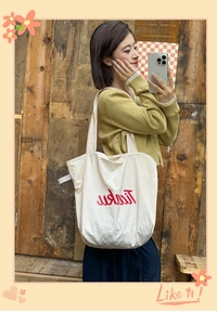 Detail of a cream-white nylon tote bag with red artistic lettering for daily commute