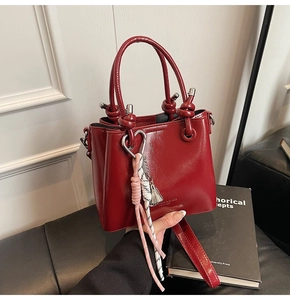 Detail of red oil wax leather bucket bag featuring decorative knots and rope tassels