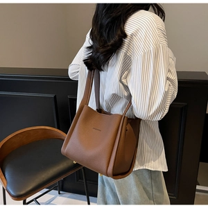 Detailed view of the brown lychee pattern leather bucket bag texture and brand logo