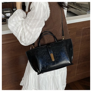 Detailed view of black oil wax leather bucket bag with gold metal buckle on a shoulder strap