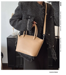 Detail of beige bucket bag with geometric embossed texture and leather top handle