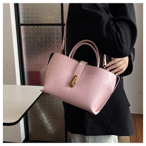 Pink waxed leather bucket bag with gold clasp shown worn over a black blazer