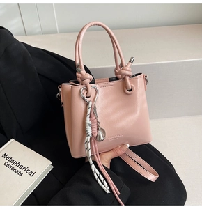 Detail of pink oil wax leather bucket bag featuring a knotted handle and decorative charm
