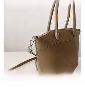 Close-up of brown textured leather bucket bag with silver metal hooks and strap