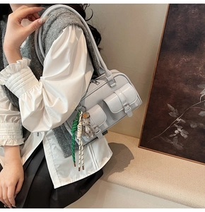 Detail view of the light blue underarm Boston bag with silver buckles and a cute bear charm