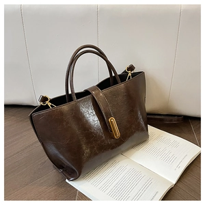 Detail of vintage oil wax leather bucket bag with gold lock and textured brown finish