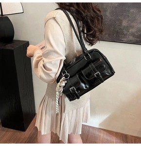 Detail of glossy black Boston bag with double front pockets and crystal bear charm