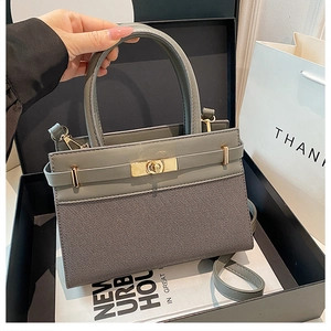 Détail du sac en cuir gris-vert montrant le fermoir métallique et le mélange de matières