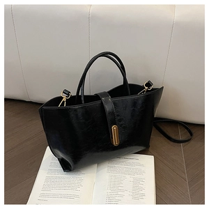 Close-up of black oil-wax leather texture and golden metal buckle on retro tote bag