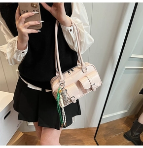 Detail view of pink glossy PU leather underarm bag with pockets and cute metal bear charm