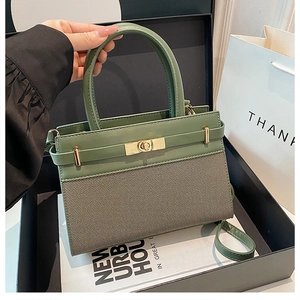 Détail du cuir vert et du tissu taupe cousus sur un sac à main trapèze structuré