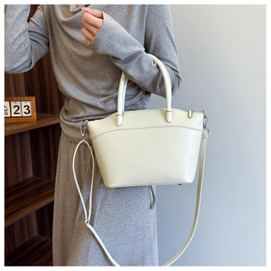 Detail of cream white bucket bag featuring geometric texture and silver metal hardware hooks