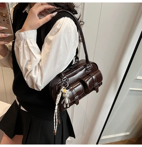 Detailed view of dark brown Boston bag with glossy finish and cute bear keychain