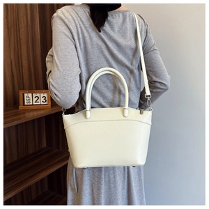 Chic beige bucket bag with textured leather and silver hardware worn as a crossbody bag