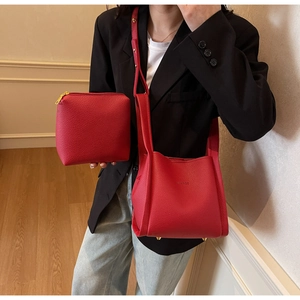Detail of red litchi texture leather bucket bag and pouch with gold metal hardware