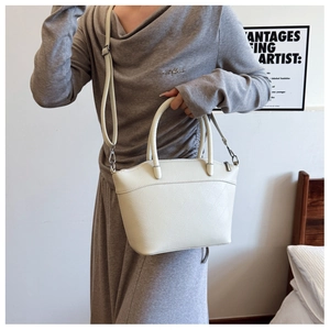 Detail view of cream minimalist bucket bag featuring fine leather texture and V-shaped stitching