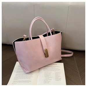 Detail of baby pink oil wax leather bucket bag with gold clasp on a fashion magazine