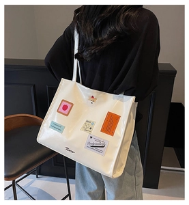 Detailansicht der weißen PU-Leder-Einkaufstasche mit Patches und Noro-Logo am Modell