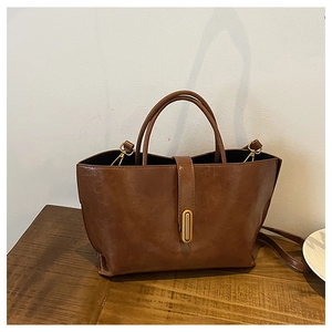 Detail view of brown oil wax leather bucket bag featuring gold buckle and crossbody strap