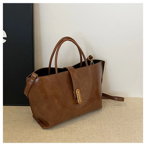 Detail of vintage brown oil wax leather bucket bag featuring a gold oval metal clasp