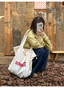 Detail view of large nylon tote bag with drawstring and red text on a female model