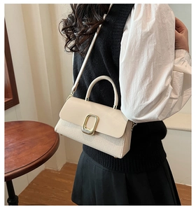 Detail of elegant beige woven texture and gold metal buckle on a stylish square handbag