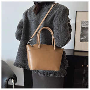Modern tan crossbody bucket bag with quilted texture shown in a minimalist home setting