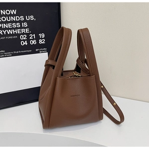 Detailed view of brown litchi grain leather bucket bag with gold hardware and strap