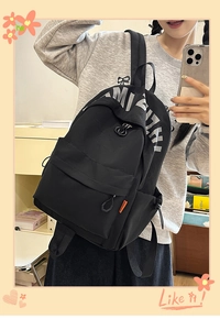 Detail view of black canvas backpack featuring large grey lettering and orange label