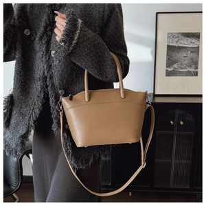 Detail view of brown trapezoid bucket bag with geometric embossed pattern and metal feet