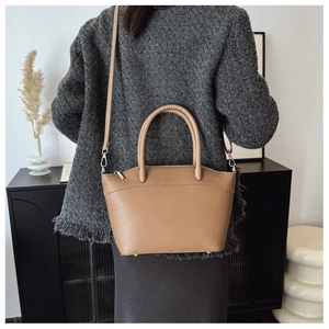 Detail of camel bucket bag with geometric embossed texture and silver metal hardware