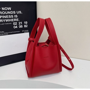 Close-up of bright red lychee leather texture and brand logo on stylish bucket bag