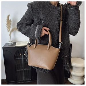 Detail of brown PU bucket bag with geometric triangle embossing and dual handles