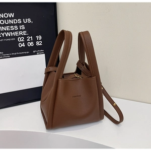 Detailed macro view of the brown lychee grain leather texture and metallic logo on the bag