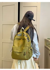 Detailed back view of an olive green casual canvas backpack worn by a model