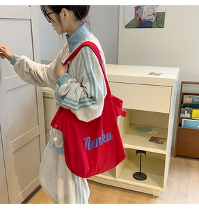 Macro view of red canvas tote bag showing durable fabric texture and blue Tianku lettering
