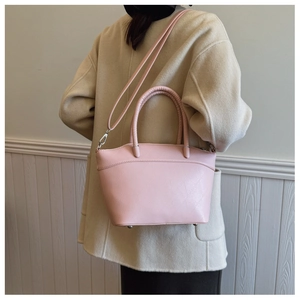Detail view of a pale pink embossed leather bucket bag worn by a model in a minimalist setting