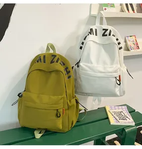Detail showing simple green and white school backpacks with MI ZHI logo on a park bench