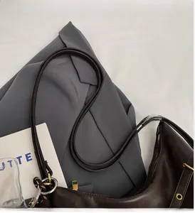 Detalle de cerca del bolso de cuero suave marrón oscuro con ojales metálicos y cremallera