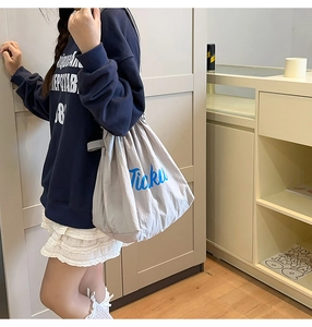 Close-up of lightweight nylon tote bag with drawstring closure and blue Ticku lettering