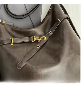 Primer plano del bolso de cuero marrón oscuro con herrajes dorados brillantes y cremalleras
