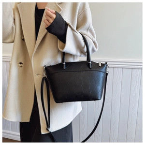 Close-up of black quilted bucket bag with silver hardware and detachable strap