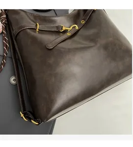 Detalle del bolso tote vintage marrón oscuro que muestra la textura de cuero suave y hebillas