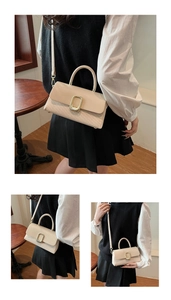 Detail of beige woven flap handbag with gold buckle and adjustable shoulder strap
