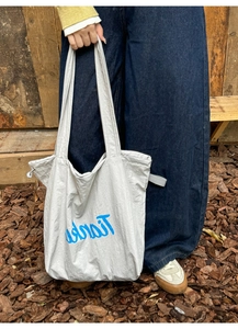 Detail view of nylon tote bag showing adjustable side drawstrings and Thanks print