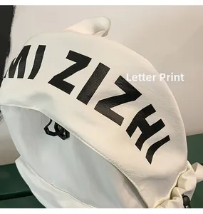 Close-up of white fashion backpack featuring bold black MI ZIZHI letter print and texture