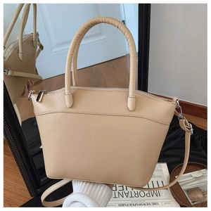 Close-up of beige bucket bag showing geometric embossed texture and silver hardware details