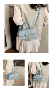 Detail of light blue crossbody bag featuring woven texture and gold metal buckle