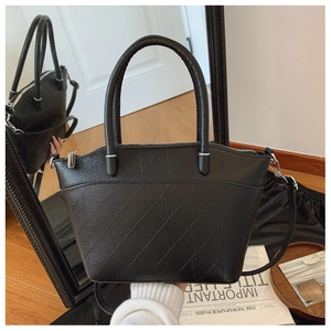 Detail of black PU bucket bag featuring geometric embossed texture and silver hardware